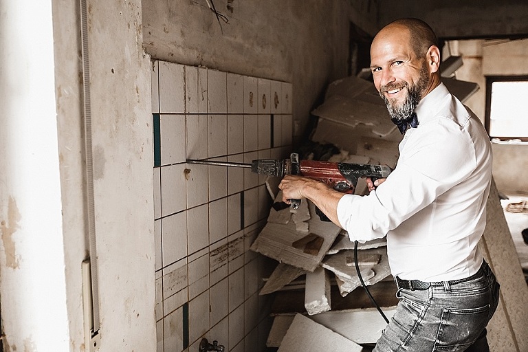 Mann mit Vorschlaghammer in der Hand entfernt Fliesenspiegel. Imagebild, Fotos für website, corporate Photography, Werbefotografie, Homepagebilder, Businessfotografie